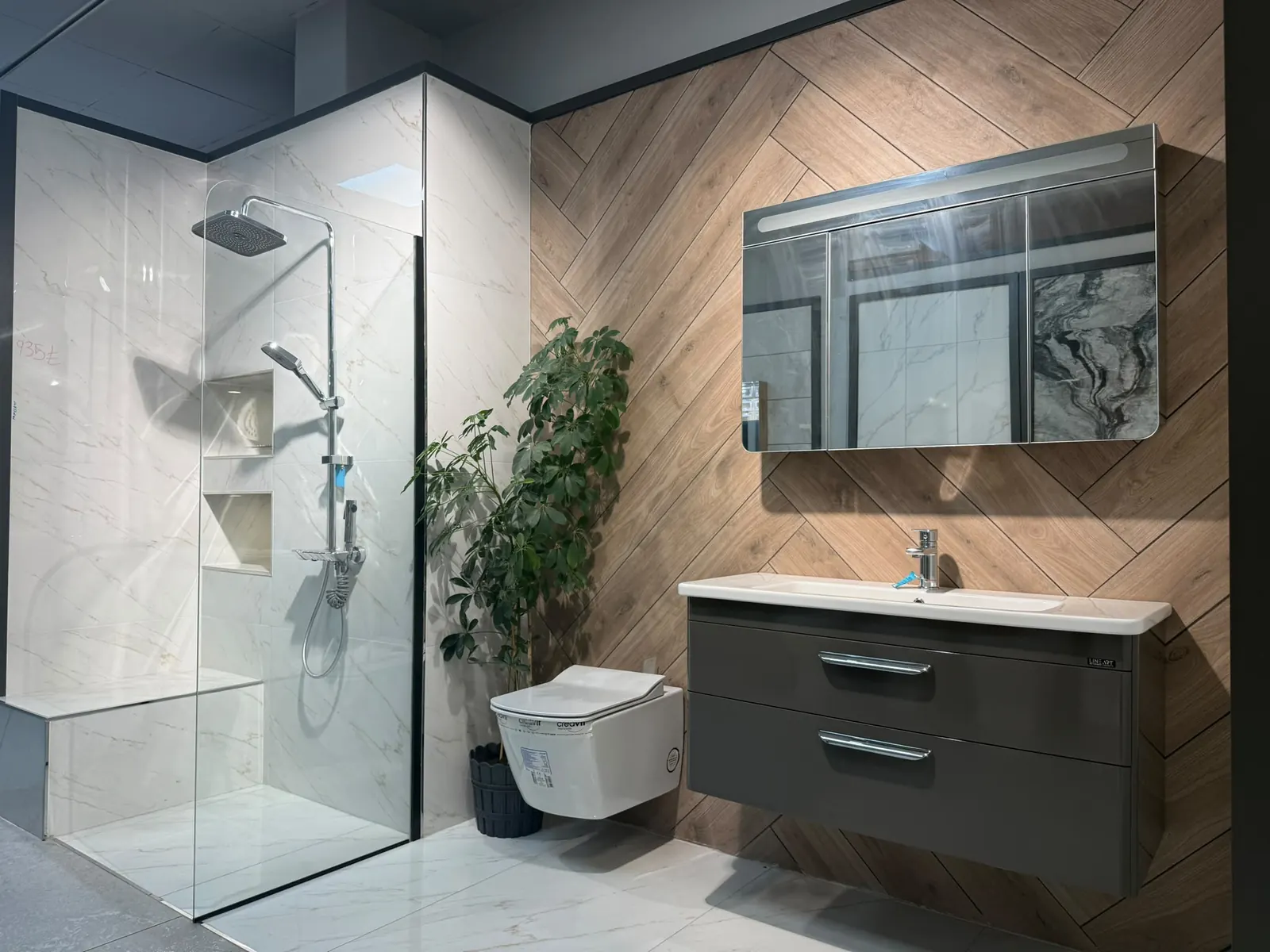 Ahşap desenli duvar, antrasit lavabo dolabı ve cam duş bölmeli banyo